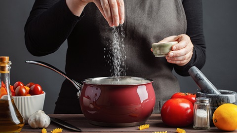 Mujer cocinando y echando sal