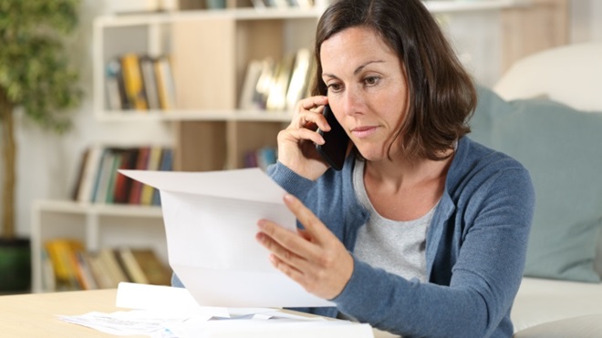 Donna preoccupata al telefono con bolletta