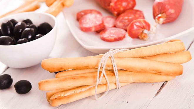palitos de pan con plato de aperitivos