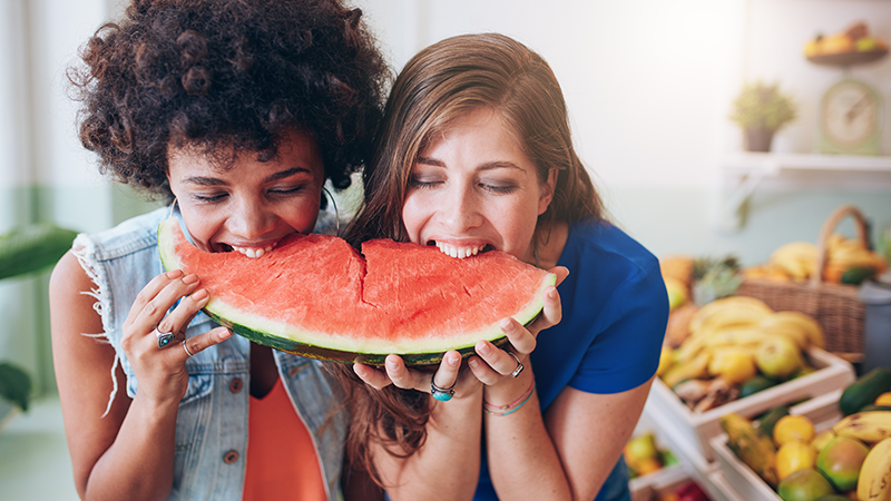 Jóvenes en una frutería comiendo sandía