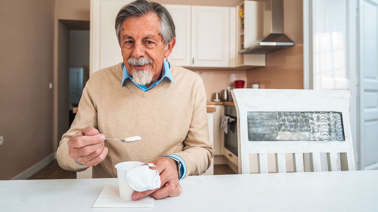 Una peronsa mayor tomando un yogur natural