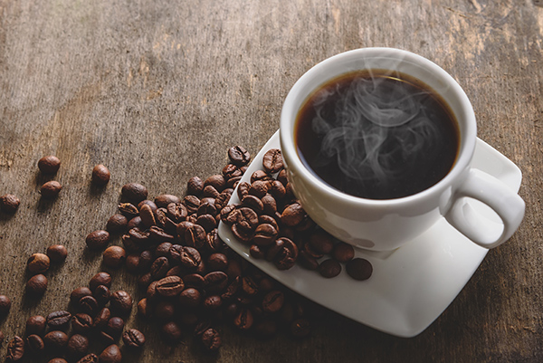 taza de café humeante con granos de café alrededor