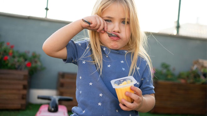 niña tomando un flan comprado en el supermercado