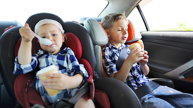 dos niños comiendo en el coche- fundas para sillitas de coche