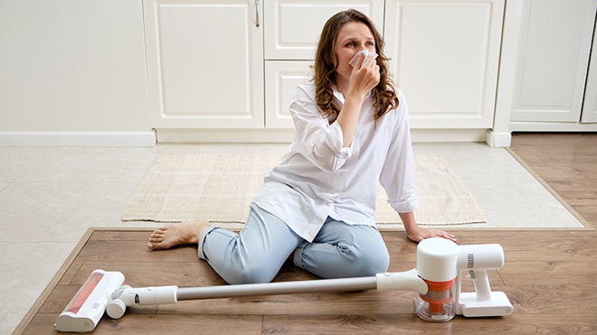 mujer con alergia y aspirador escoba