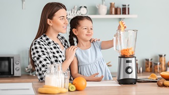 mujer y niña usando batidora de vaso