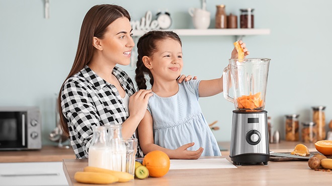 mujer y niña usando batidora de vaso