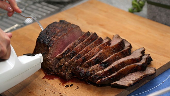 Cortando un asado de carne con un cuchillo electrico