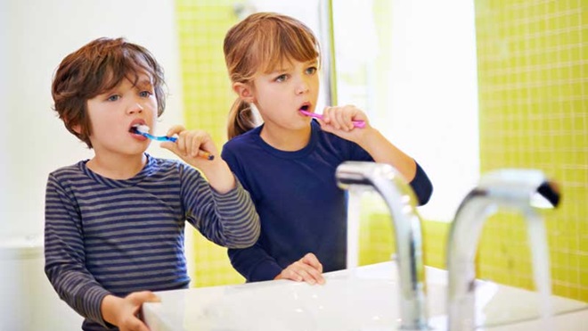 Niño y niña cepillándose los dientes en el cuarto de baño