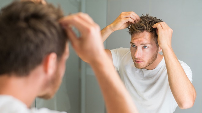 Chico mirándose el cuero cabelludo en el espejo