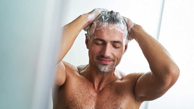 Hombre enjabonándose el pelo en la ducha