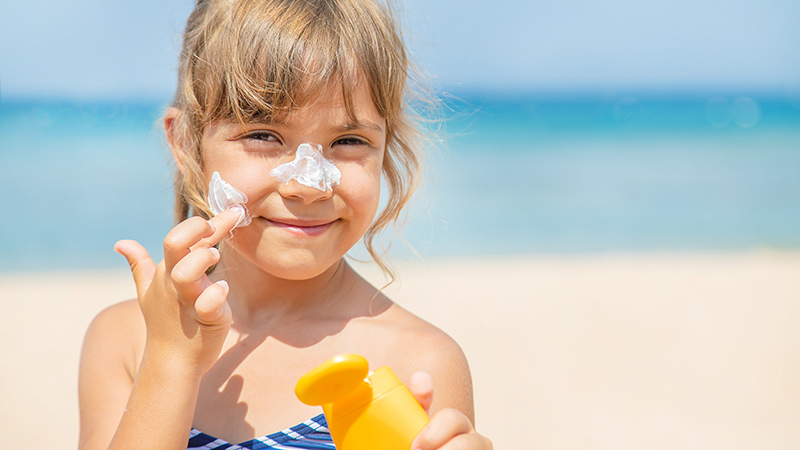 Niña echándose crema en la cara
