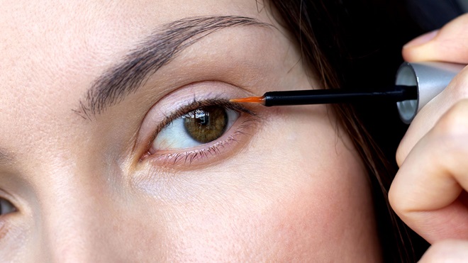 mujer aplicando en el párpado sérum alargador de pestañas