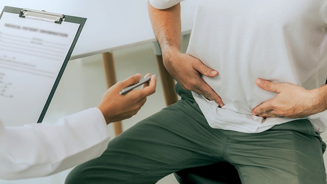 Enfermo tocándose la tripa en la consulta médica