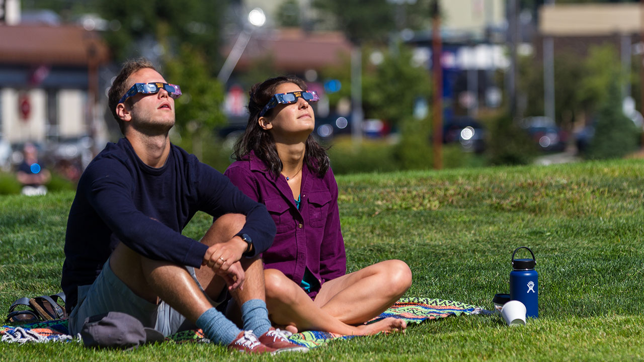 chico y chica mirando el sol protegidos con gafas para eclipses