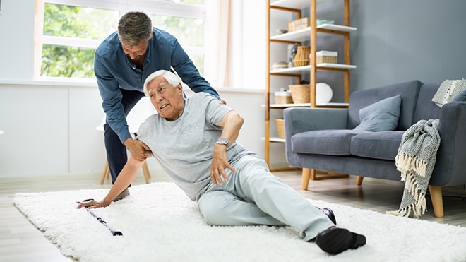 una persona ayuda a levantarse del suelo a un mayor que se ha caído