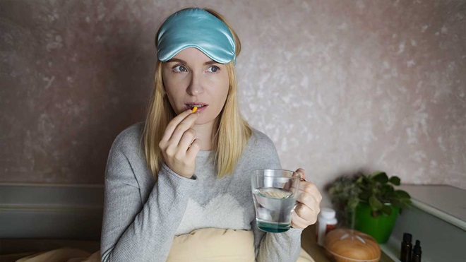 chica preparándose para dormir y tomando una pastilla
